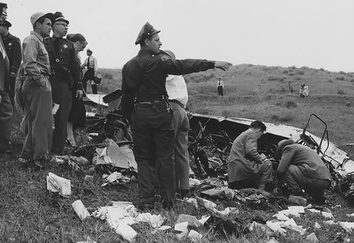 A vintage black and white photo of police and investigators examining the airplane crash that killed all on board when it went down in Turnbull Canyon, Whittier, CA, in 1952.